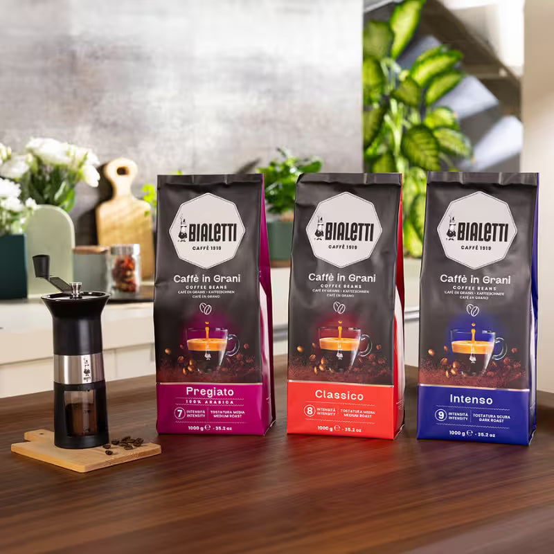 Bolsas de café en grano Bialetti en mesa: variedades Clásico, Pregrado e Intenso
