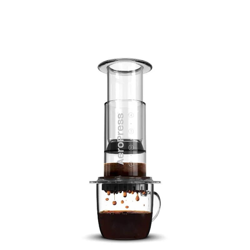 Prensa de café con cilindro transparente, filtro negro y base oscura con asa