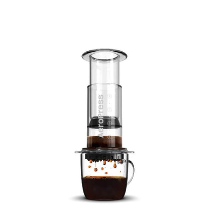 Prensa de café con cilindro transparente, filtro negro y base oscura con asa