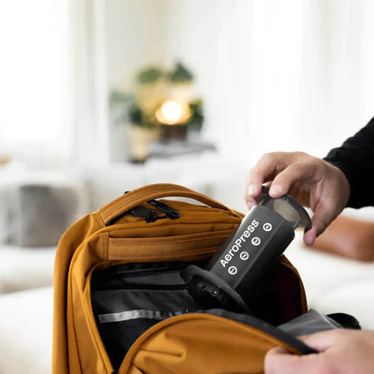 AeroPress en una mochila, dispositivo negro con logotipo visible sobre una funda