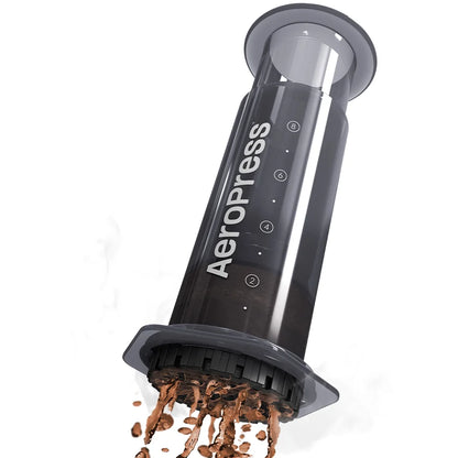 Prensa de café negra AeroPress XL con tapa abierta y café molido cayendo