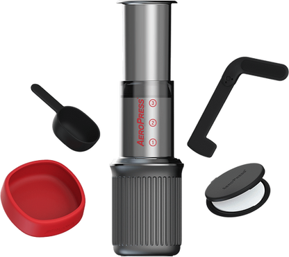 AeroPress GO con componentes: cilindro, base acanalada y tapas negra y roja