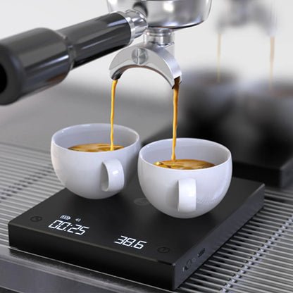 Balanza digital negra con dos tazas blancas sobre la plataforma y lectura en pantalla