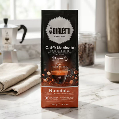 Bolsa de café molido Bialetti con avellanas (250 g) con taza e ilustración de avellanas.