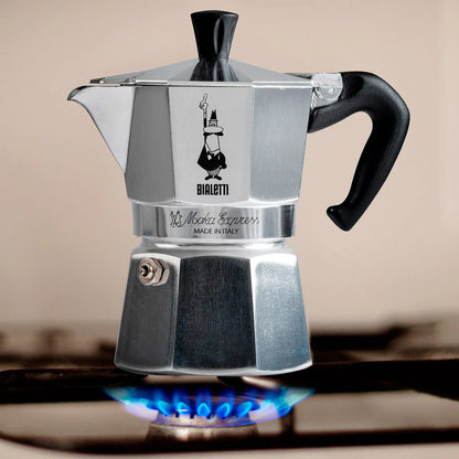 Cafetera italiana Moka Express Bialetti de acero con asa negra y válvula sobre cocina
