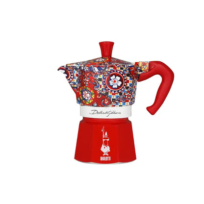 Cafetera moka con estampado multicolor, base roja y asa curva roja, vista frontal