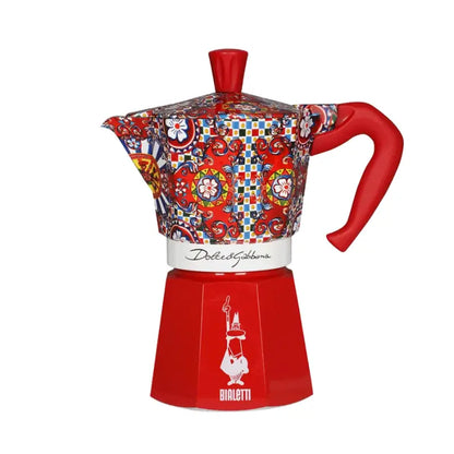 Cafetera moka multicolor con base roja, asa roja y franja blanca, vista inclinada