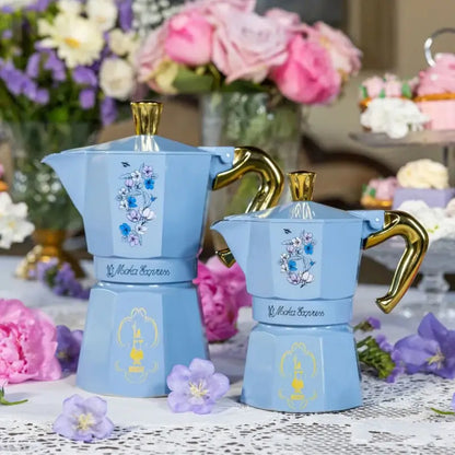 Cafetera moka de aluminio azul celeste con asa dorada y grabado floral en la jarra