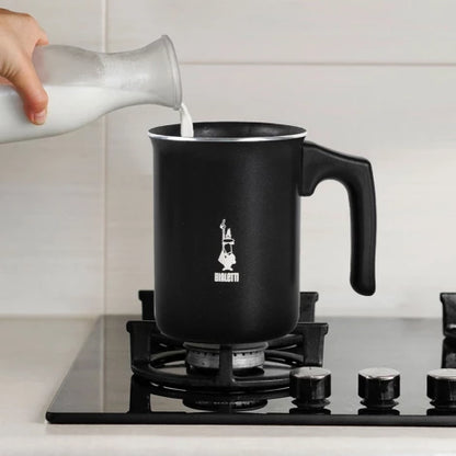 Espumador de leche negro Bialetti con asa, vertiendo leche desde un recipiente