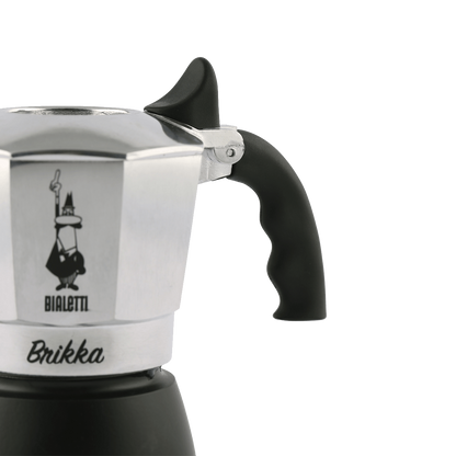 Cafetera italiana compacta de acero pulido con base negra y asa ergonómica de plástico.