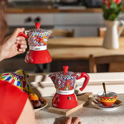 Cafetera moka roja de inducción con diseño multicolor, sostenida en la mano
