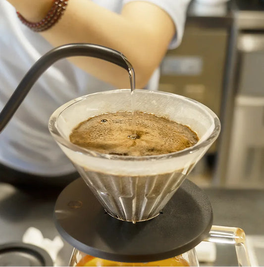 Goteador de café Crystal Eye Timemore con café vertiéndose en el cono de cristal