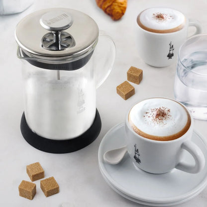 Espumador de leche Bialetti con tapa metálica y espuma en tazas con canela.