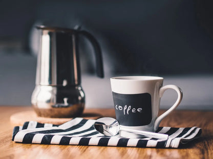 Cafetera italiana Bialetti Kitty de acero blanca con asa negra, lista para servir