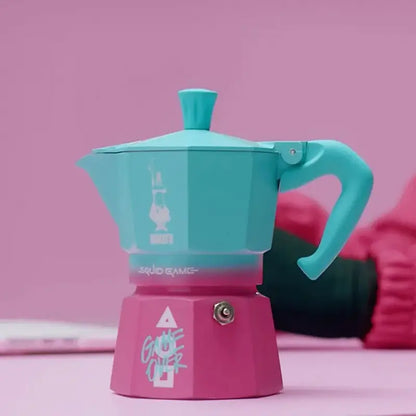 Cafetera italiana moka turquesa con base magenta, tapa con chimenea y asa
