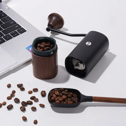 Molino de café con tapa abierta y granos de café, cuerpo negro y base de madera