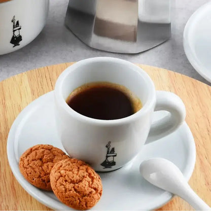 Taza de espresso blanca con plato, café y galletas; ilustración Bialetti negra