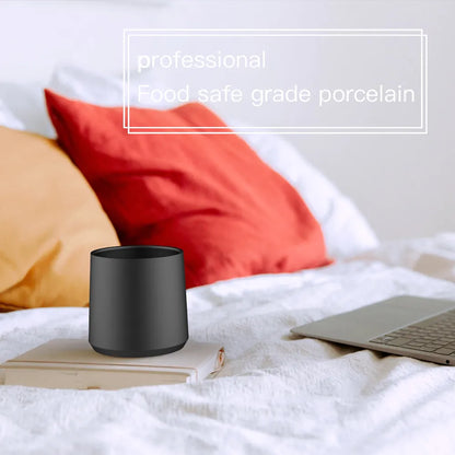 Vaso de café de cerámica negro en mesa, diseño cilíndrico
