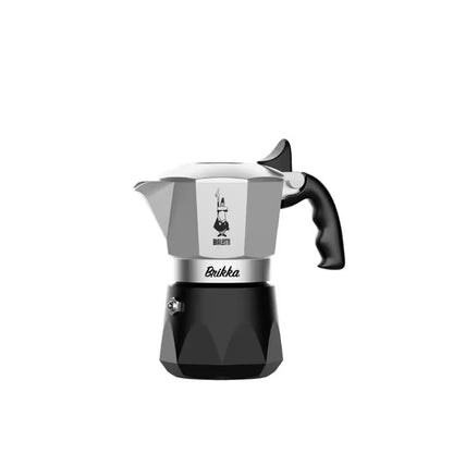Cafetera italiana de acero y base negra, vista frontal con asa negra y tetera superior.