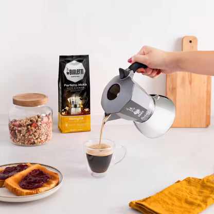 Cafetera moka Bialetti Brikka Induction gris vertiendo café con mano
