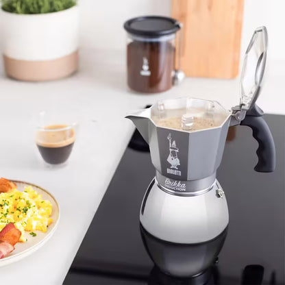 Cafetera moka Bialetti Brikka Induction gris con café en vertido y taza