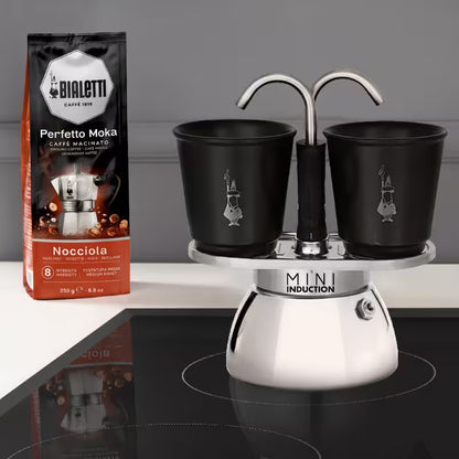 Cafetera Mini Induction con dos tazas negras sobre base metálica