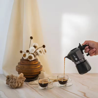 Cafetera Bialetti Brikka noir vertiendo café, mano sujetando la empuñadura