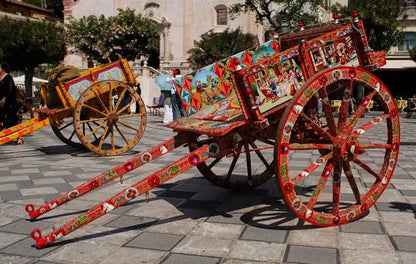 Carro decorativo multicolor con detalle tipo patrón, ruedas grandes y estructura roja