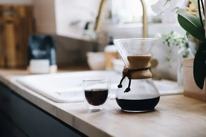 Cafetera Chemex de vidrio con café en preparación y filtro de papel