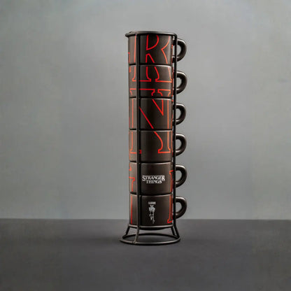 Torre de tazas apilables negras con gráficos rojos y asas, sobre soporte metálico