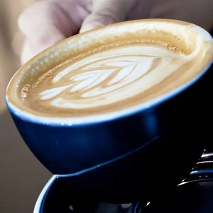 Taza EGG azul con café con leche y espuma sobre plato a juego