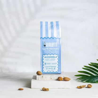 Bolsa azul de café molido Bialetti Mandorla con frutos sobre base blanca
