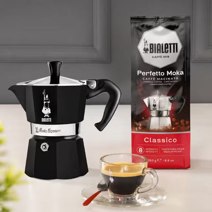 Cafetera moka italiana Bialetti negra con asa y taza de café