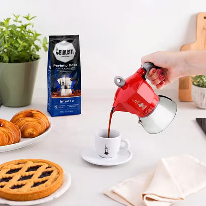 Cafetera italiana moka Bialetti roja vertiendo café a una taza blanca