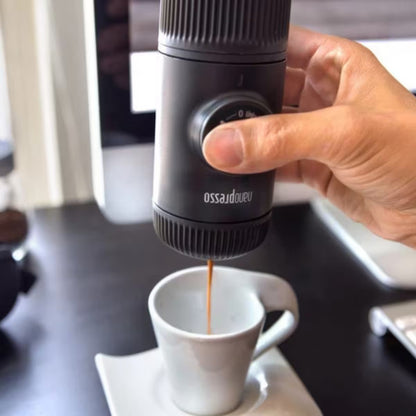 Cafetera portátil negra Nanopresso vertiendo en taza blanca con mano