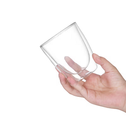 Vaso de vidrio de doble pared transparente en mano, vista lateral del borde