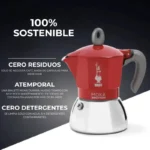 Una Cafetera moka de aluminio y acero inoxidable de color roja se exhibe junto a un texto en español que destaca su sostenibilidad, cero residuos, atemporalidad y limpieza sin detergente.