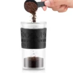 Llenanando con café la cafetera de viaje prensa francesa negra con tapa.