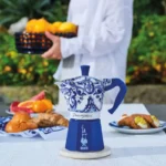 Cafetera Moka Bialetti de porcelana azul y blanca sobre una mesa, inspirada en el Mediterráneo y el arte italiano.