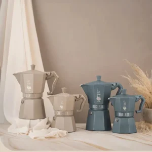 Cuatro cafeteras Moka Octagonal en una mesa, junto a una cortina, representando la fusión de tradición y modernidad.
