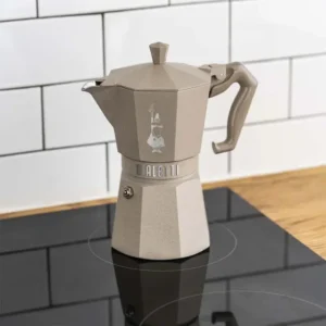 Cafetera Italiana Moka Octagonal sobre una cocina de inducción, con un elegante fondo de azulejos en blanco.